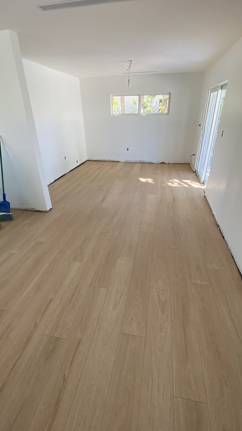 Completed light wood-look plank flooring across a bright open living area