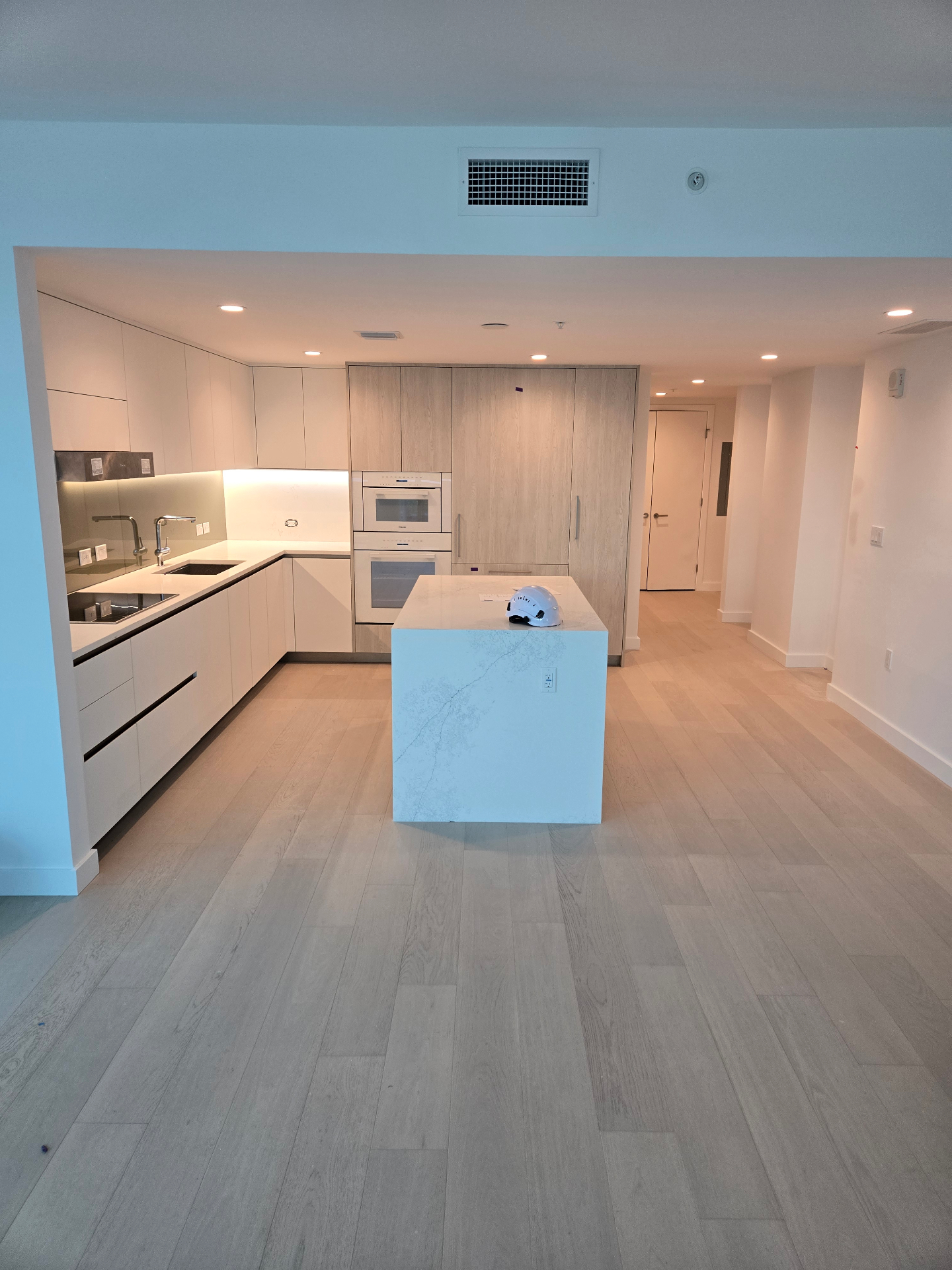 Completed light-toned plank flooring throughout a modern kitchen and open living area