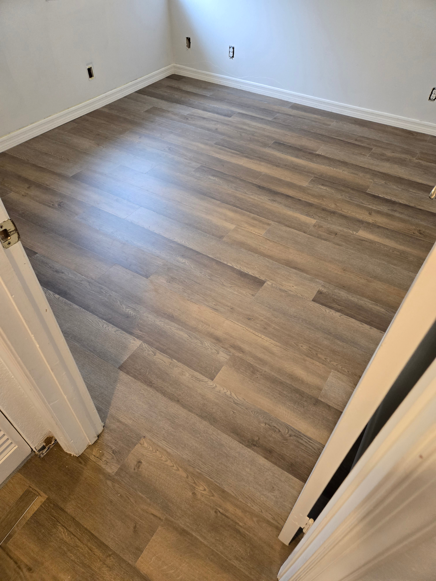 Completed gray wood-look plank flooring in a room with white walls and baseboards